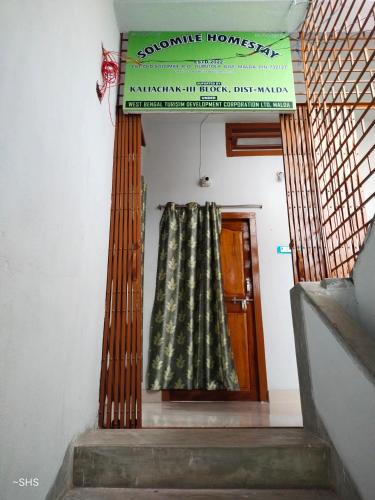 una puerta con una cortina delante de una escalera en Solomile Homestay en Farakka