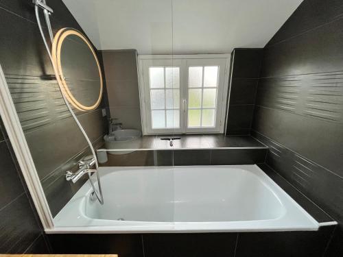 eine weiße Badewanne im Bad mit Spiegel in der Unterkunft Kelerdutbay fr, accès direct à la mer in Plouguerneau