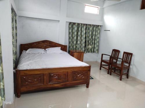 a bedroom with a wooden bed and two chairs at Solomile Homestay in Farakka