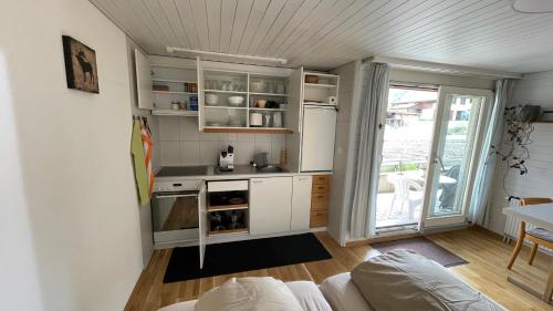uma pequena cozinha com armários brancos e um fogão em Zimmer in den Voralpen em Grub