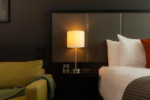 a hotel room with a bed and a lamp and a chair at Rydges Wellington Airport in Wellington