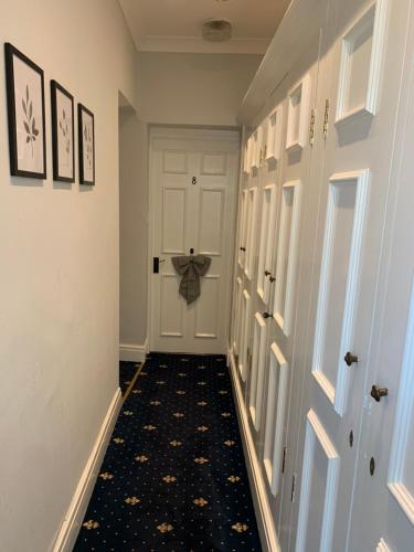 a hallway with a white door and a black rug at The Old Coach House in Blackpool