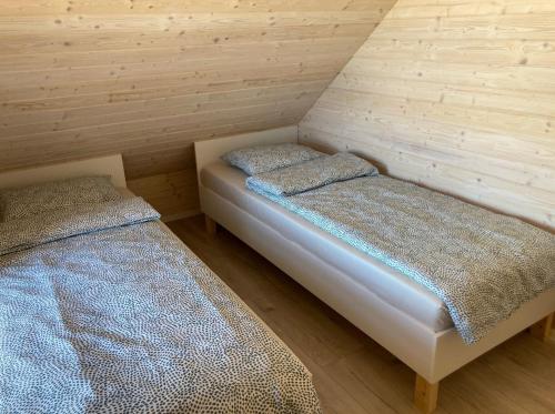 2 Betten in einem Zimmer mit Holzwänden in der Unterkunft Klimatyzowany domek letniskowy in Mielno