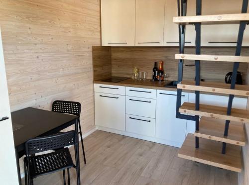eine Küche mit weißen Schränken sowie einem Tisch und Stühlen in der Unterkunft Klimatyzowany domek letniskowy in Mielno