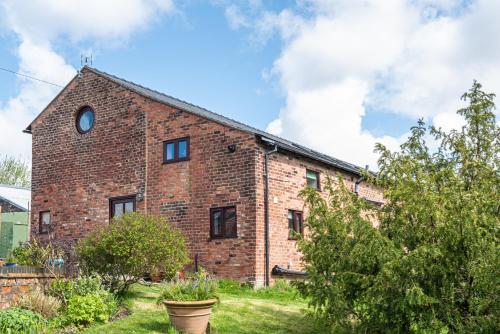 a brick building with a clock on the side of it at Brook Farm Barn in Frodsham