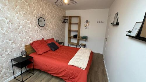 a bedroom with a bed with a red comforter at Petite maison en pierre au pied de la voie verte in Ploërmel
