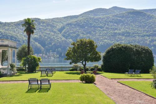 un parque con sillas, una palmera y un lago en Apt. 123 - Beautiful apartment on the lake en Porto Ceresio