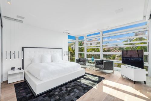 een slaapkamer met een wit bed en een groot raam bij Indulge in Waterfront Elegance Your Ultra Luxury Miami Beach Estate Beckons! in Miami