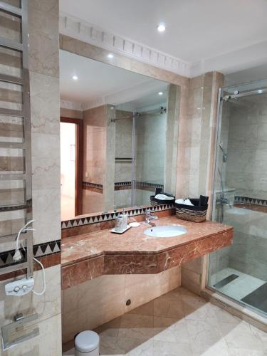een badkamer met een wastafel, een douche en een spiegel bij Charmant appartement in Marrakesh
