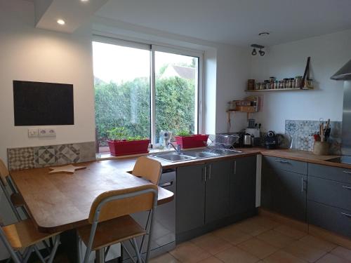 une cuisine avec une table, un évier et une fenêtre dans l'établissement Petite maison près de Disneyland, à Magny-le-Hongre