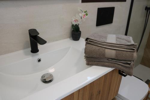 een wastafel in de badkamer met twee handdoeken en een vaas met bloemen bij Villa Lucia at Santa Rosalia Lake & Life Resort in Los Alcázares