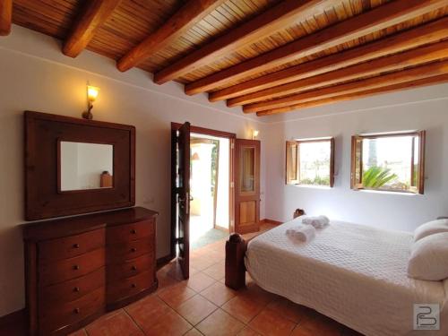 1 dormitorio con cama, tocador y espejo en Casa Bet con piscina y jardín., en Sant Miquel de Balansat