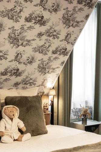 a teddy bear sitting on a bed in a bedroom at Hotel Biskajer by CW Hotel Collection - Adults Only in Bruges