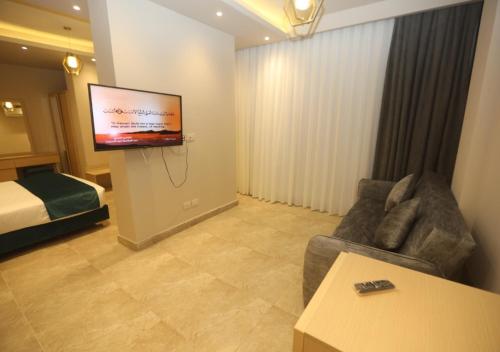 uma sala de estar com um sofá e uma televisão num quarto de hotel em Coast Hotel em El Alamein