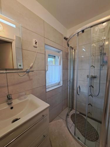 ein Bad mit einer Dusche und einem Waschbecken in der Unterkunft Jázmin Apartman Zalakaros in Zalakaros
