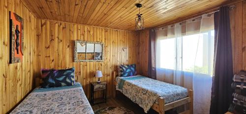 1 dormitorio con 2 camas en una cabaña de madera en Hostal Sol y Luna en Santiago