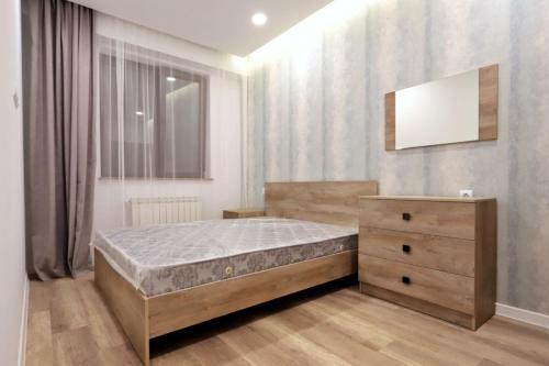 a bedroom with a bed and a dresser and a mirror at Kvartira dizaynerskaya in Yerevan