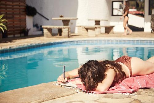 a woman laying on a towel next to a swimming pool at Beachside stay at Villa ViYarte in San Juan del Sur
