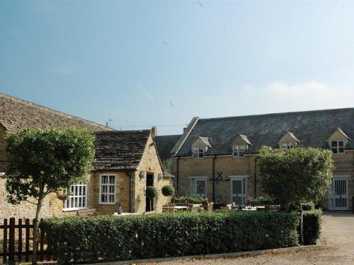 a group of buildings with a fence and trees at The White Horse Inn in Deddington