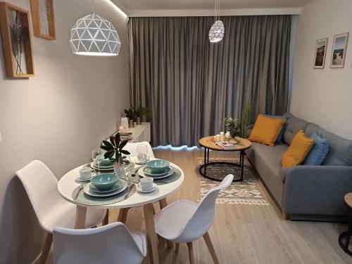 een woonkamer met een tafel en een bank bij Apartament Grabówek in Gdynia