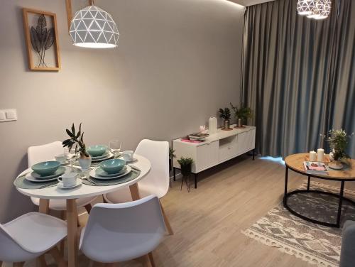 een woonkamer met een tafel en witte stoelen bij Apartament Grabówek in Gdynia