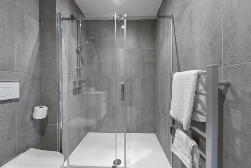 a bathroom with a glass shower with a toilet at Stylish 1BR Retreat at Station House Milton Keynes in Milton Keynes