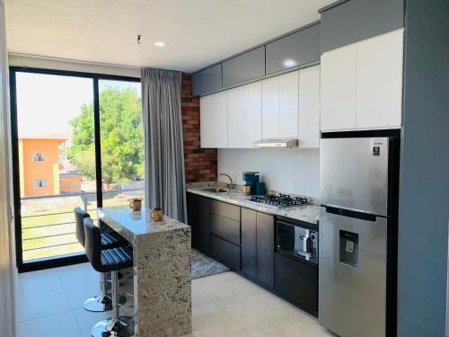 a kitchen with white cabinets and a counter with a window at New Modern Condo with Air-condition in Zapotlanejo