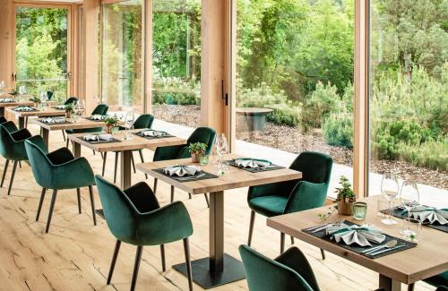 een eetkamer met houten tafels en groene stoelen bij Taubers Bio Vitalhotel in Chienes