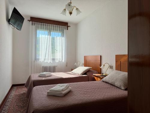 - 2 lits dans une petite chambre avec fenêtre dans l'établissement Triacastela Sunset Terrace, à Tríacastela