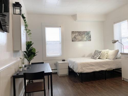 1 dormitorio con cama, mesa y escritorio en Cozy Bachelor Condo l Downtown l WiFi & Smart TV, en Moose Jaw