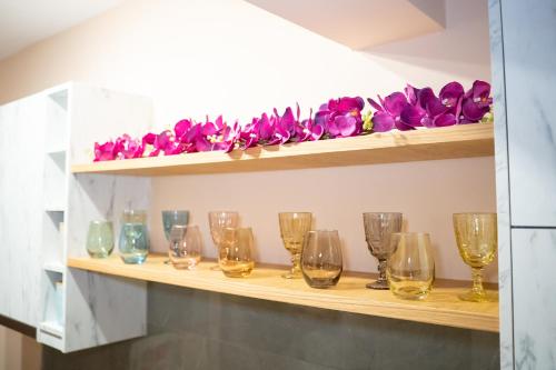 a row of wine glasses on a shelf with purple flowers at Kostis Luxury Apartment in Agrinion