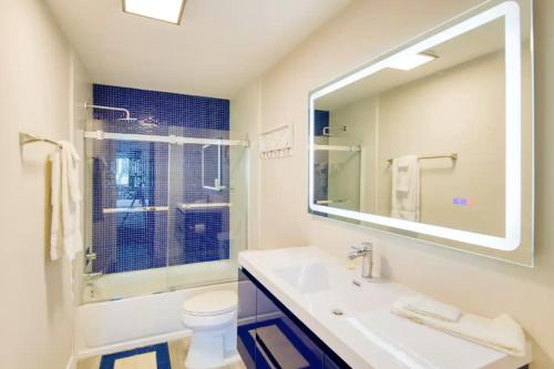 ein Badezimmer mit einem Waschbecken, einem WC und einem Spiegel in der Unterkunft Dog friendly condo with beach access, hot tub, firepit in West Palm Beach