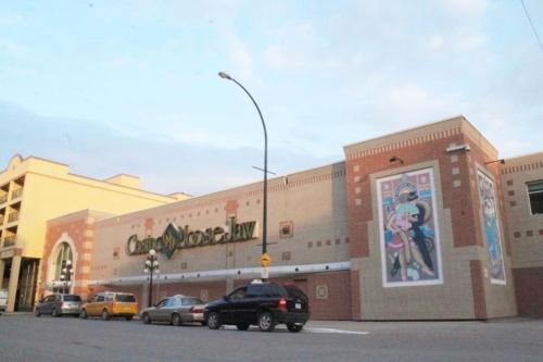 a shopping mall with cars parked in front of it at Large 1-bedroom Condo l Downtown l WiFi & Smart TV in Moose Jaw
