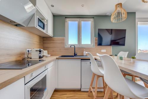 une cuisine avec des armoires blanches et une table et des chaises dans l'établissement Sunset Duplex - Grand-Rond, Jardin des plantes, centre-ville, 2 BDRs 60m2, AC, Netflix - T3 60m2 avec clim, à Toulouse