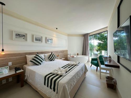 a bedroom with a bed and a bathroom with a tub at Passagem Concept Hotel e Spa in Cabo Frio