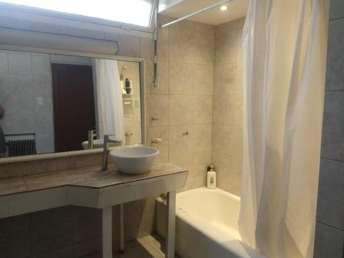 uma casa de banho com um lavatório, uma banheira e um espelho. em Habitaciones con baño compartido en Departamento Mid Century Modern em Mendoza