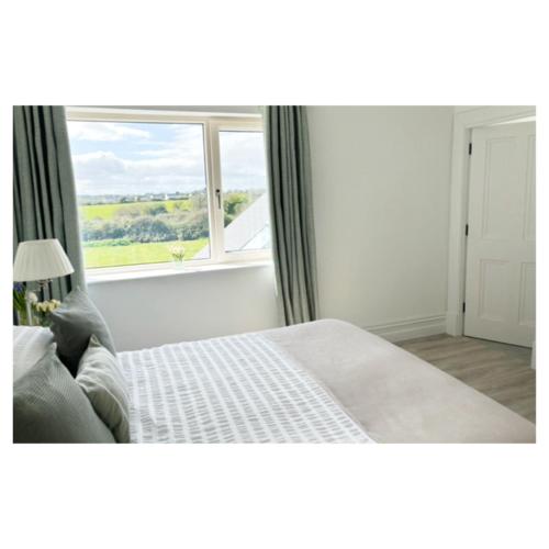 a bedroom with a large bed and a window at Eastbury House near Garryvoe Hotel & Ballymaloe House in Cork