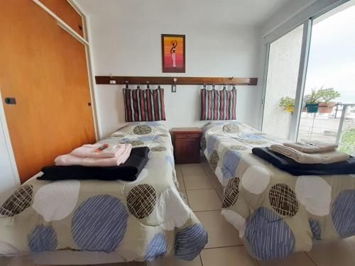 1 dormitorio con 2 camas y ventana en Departamento Fragueiro 2414 terraza exclusiva en Córdoba