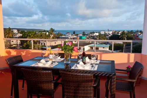 una mesa con copas de vino y flores en el balcón en Torre Mar Galapagos Boutique Suites, en Puerto Ayora