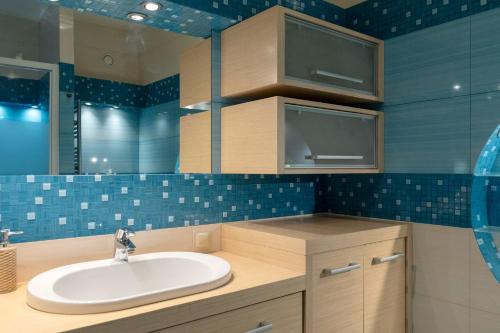 a bathroom with a sink and blue tiled walls at Kraków Główny Apartment - Parking, Workspace - by Rentujemy in Krakow
