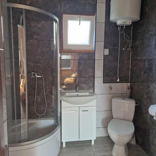 ein Badezimmer mit Dusche, Toilette und Waschbecken in der Unterkunft Domki Olimp Resort Blisko Morza in Sarbinowo