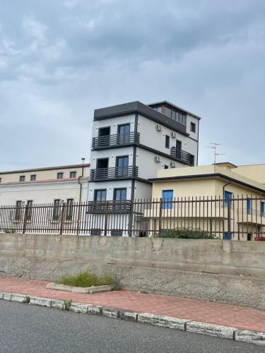 a tall white building with a fence in front of it at Il Vicoletto Bovalino - B&B in Bovalino Marina
