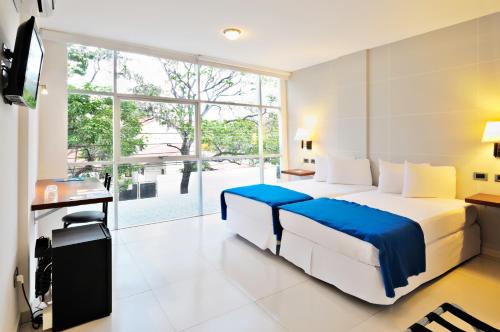 a bedroom with a bed and a desk and a window at Hotel LP Santa Cruz Centro in Santa Cruz de la Sierra
