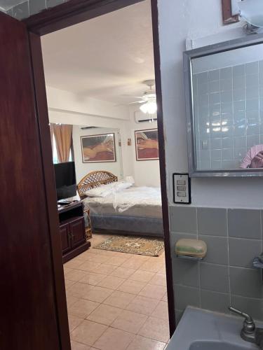 uma casa de banho com um quarto com uma cama e um espelho. em TRANQUILO Y ESPACIOSO DEPARTAMENTO AMBASSADOR em Campo de Carabobo