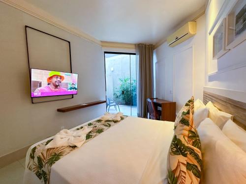 a bedroom with a bed with a tv on the wall at Passagem Concept Hotel e Spa in Cabo Frio