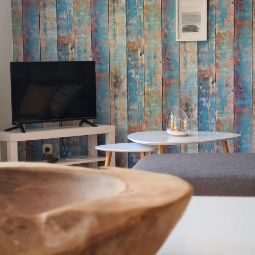 a living room with a tv and two tables at Ferienwohnung STRANDGUT in Behrensdorf