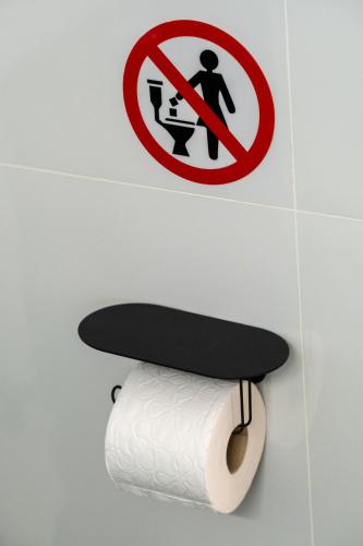 a roll of toilet paper in a bathroom with a sign at Charmant in Athens
