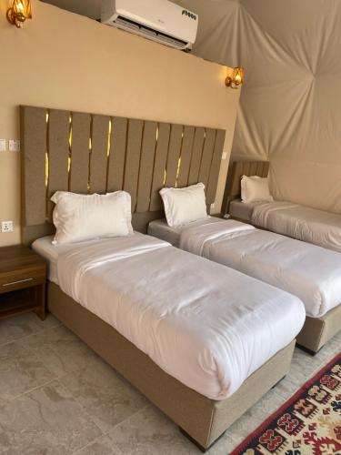 2 bedden met witte lakens in een kamer bij Wadi Rum Joy camp in Disah