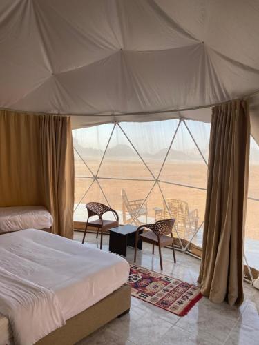 een slaapkamer met een bed en uitzicht op de woestijn bij Wadi Rum Joy camp in Disah