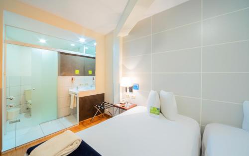 1 dormitorio con cama blanca y ducha en Hotel LP Columbus, en La Paz